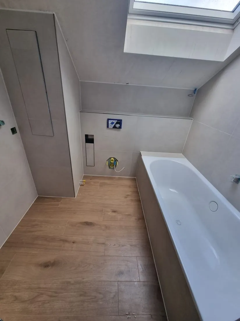 Renoviertes Dachbad mit Holzoptik-Boden und Badewanne